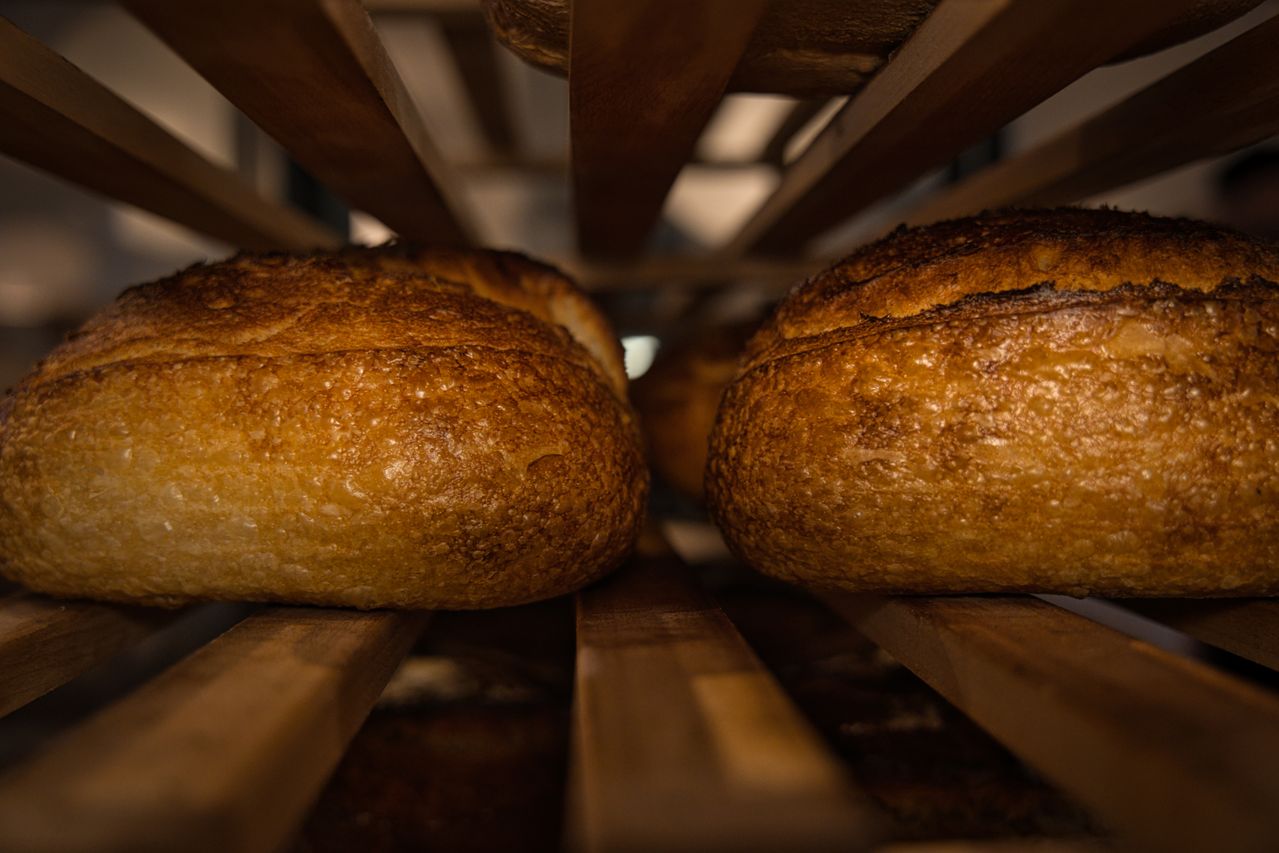 Due pagnotte a lievitazione naturale in raffreddamento su griglia di legno