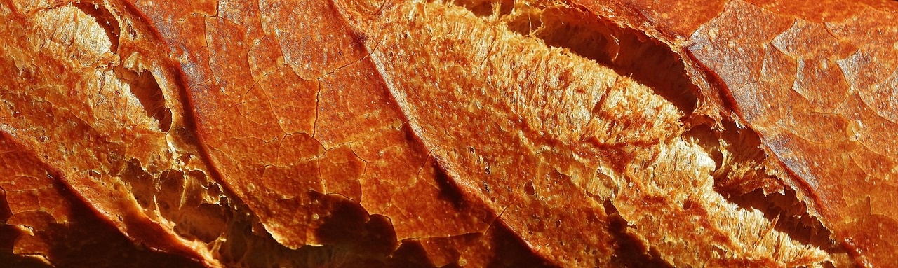 Dettaglio ravvicinato della crosta di una baguette con incisioni profonde