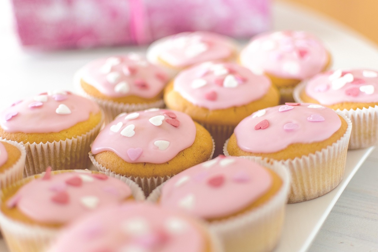 Piccoli dolcetti in pirottino con glassa rosa e decorazione a cuori